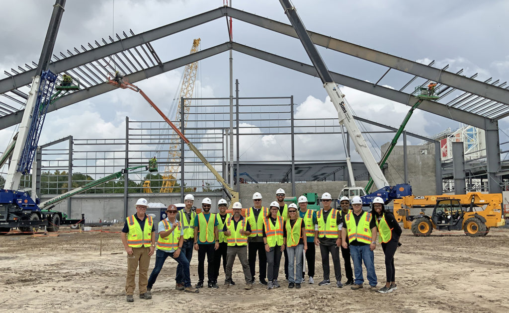 Team members from ROSETTI, the architect of Miller Electric Center, and Coach Pederson and General Manager Trent Baalke inside the construction area of Miller Electric Center's indoor practice field.